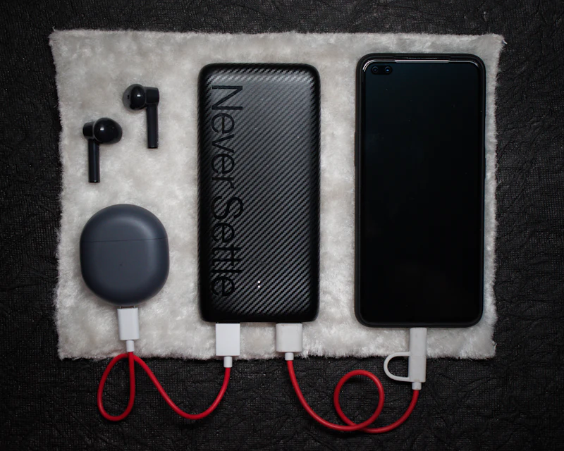 Power bank, wireless earbuds and charging cable on a stone surface